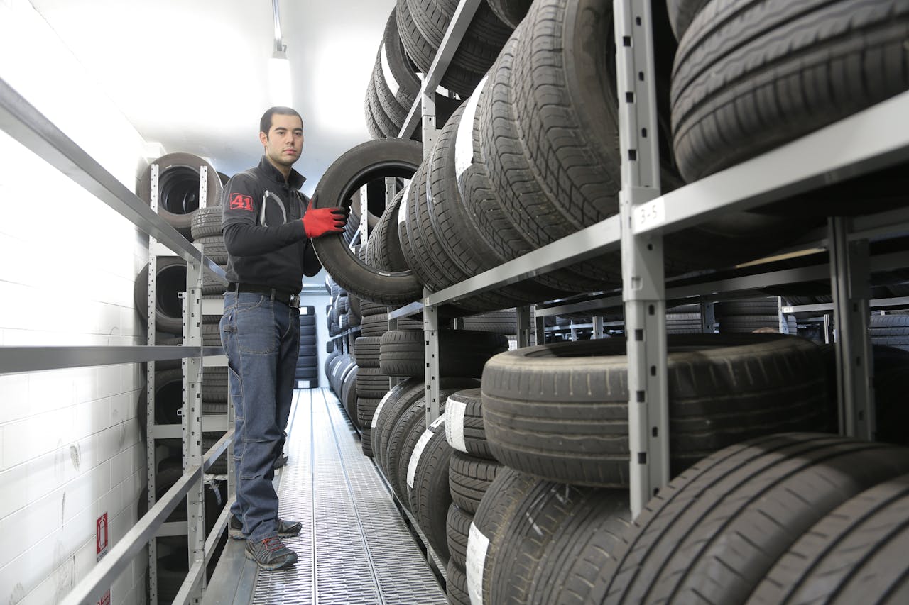 who-we-are Mechanic places a tire on a rack in an indoor warehouse storage facility.